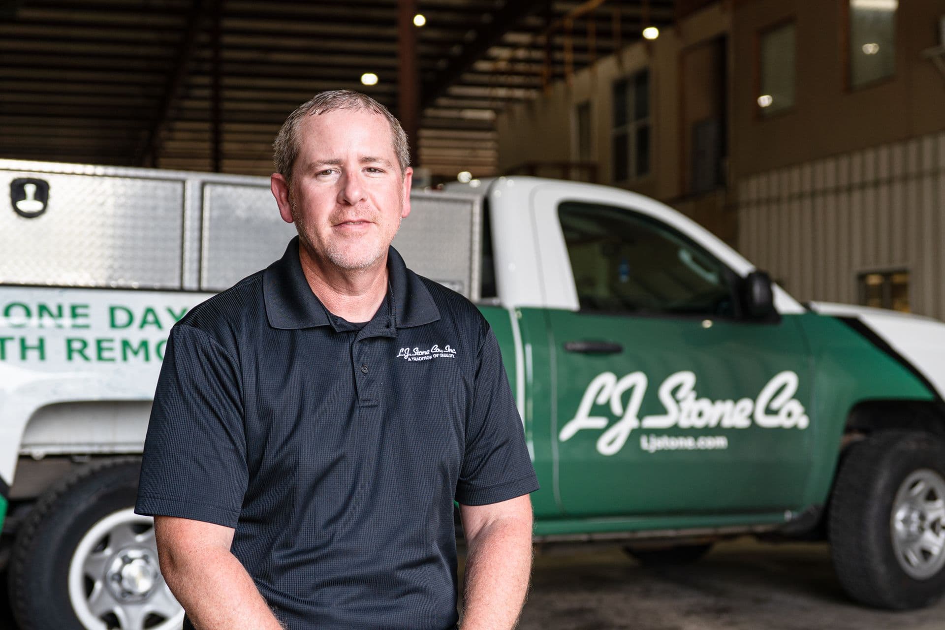L&J Stone Co. employee standing in front of company service vehicles in warehouse